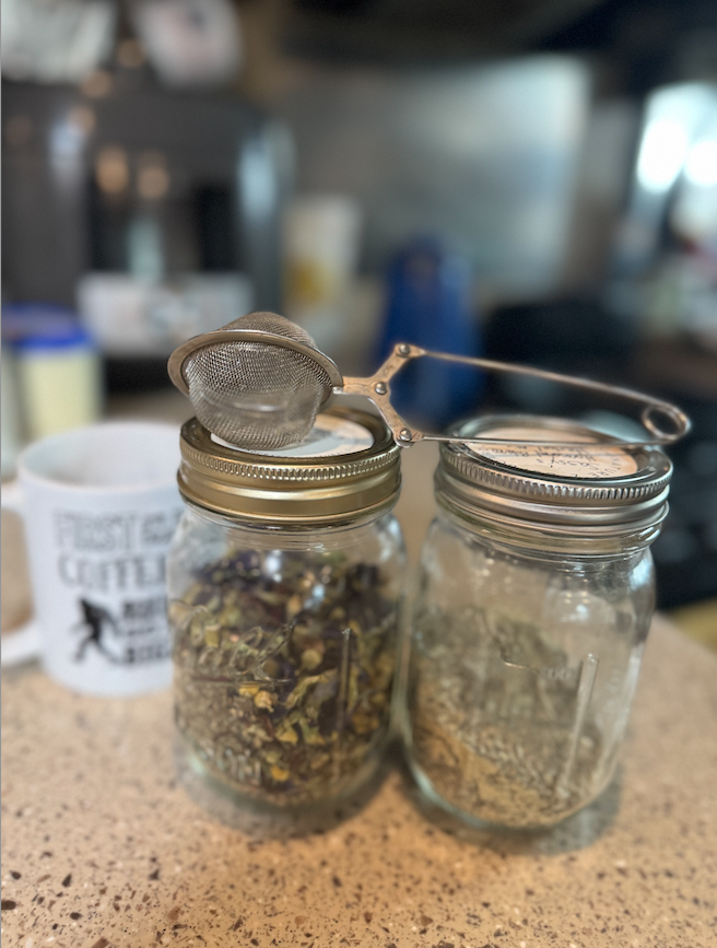 Handcrafted teas made with organic ingredients. Mason jars filled with dried herbs for tea, with a tea strainer resting on top, in Hannah's cozy RV kitchen.